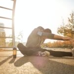 flexible sportsman stretching on sports ground